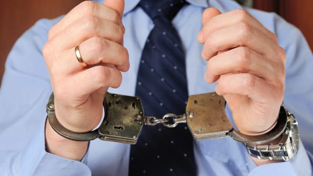 Mann in Anzug und Kravatte mit Handschellen Mann in Anzug und Kravatte mit Handschellen