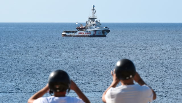 Touristen fotografieren das spanische Rettungsschiff «Open Arms» vor Lampedusa nahe der italienischen Küste. Touristen fotografieren das spanische Rettungsschiff «Open Arms» vor Lampedusa nahe der italienischen Küste.