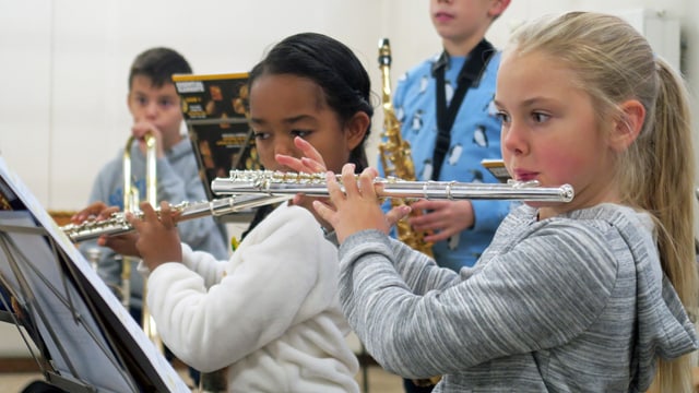Zwei Mädchen spielen während des Musikunterrichts auf einer Querflöte. Zwei Mädchen spielen während des Musikunterrichts auf einer Querflöte.