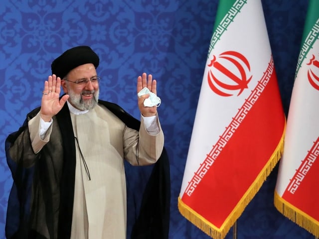Ebrahim Raisi grüsst an der Pressekonferenz und hebt beide Hände in die Luft. Ebrahim Raisi grüsst an der Pressekonferenz und hebt beide Hände in die Luft.