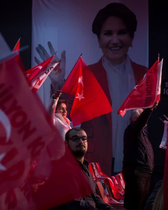 Anhänger halten Türkei-Fahnen hoch vor einem überlebensgrossen Bild von Aksener. Anhänger halten Türkei-Fahnen hoch vor einem überlebensgrossen Bild von Aksener.