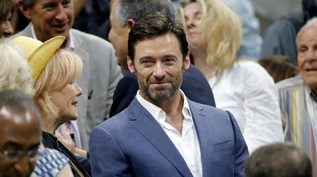Hugh Jackman in blauem Anzug und weissem Hemd auf den Zuschauerrängen.