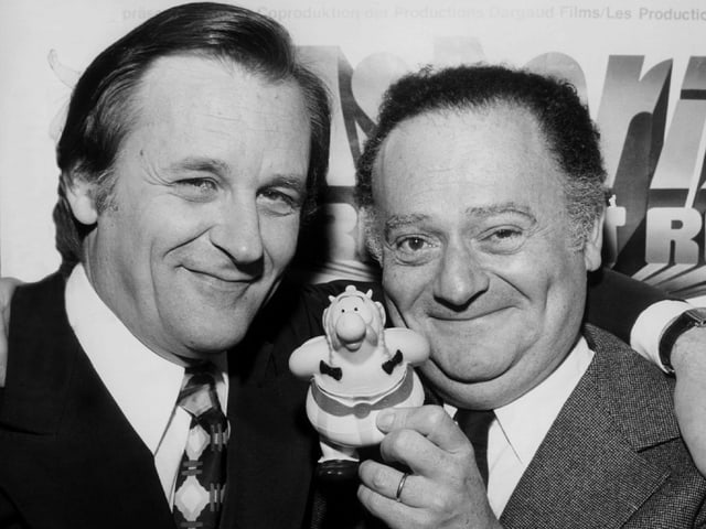 Zwei Männer und eine kleine Obelix-Figur. Zwei Männer und eine kleine Obelix-Figur.