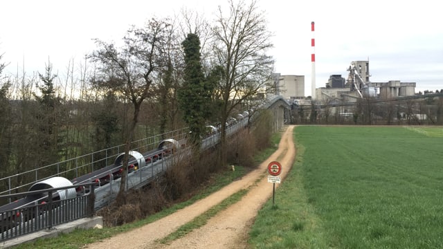 Förderband neben Feldweg, im Hintergrund Fabrik mit Kamin Förderband neben Feldweg, im Hintergrund Fabrik mit Kamin