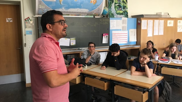 Ein Mann in rosa Poloshirt vor einer Klasse Ein Mann in rosa Poloshirt vor einer Klasse