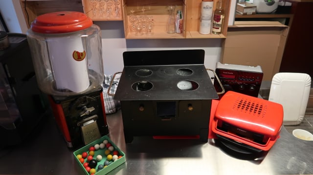 Ein Kaugummispender, ein Spielzeugholzherd, ein roter Kofferplattenspieler Ein Kaugummispender, ein Spielzeugholzherd, ein roter Kofferplattenspieler