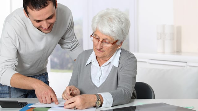 Mann zeigt Seniorin etwas auf Dokument. Mann zeigt Seniorin etwas auf Dokument.