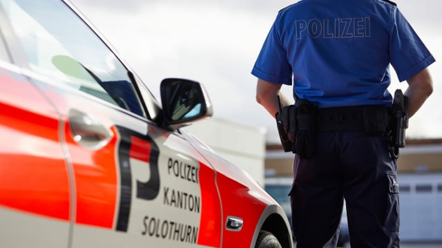 Ein Polizist steht neben einem Polizeiauto mit der Aufschrift Polizei Kanton Solothurn. Ein Polizist steht neben einem Polizeiauto mit der Aufschrift Polizei Kanton Solothurn.