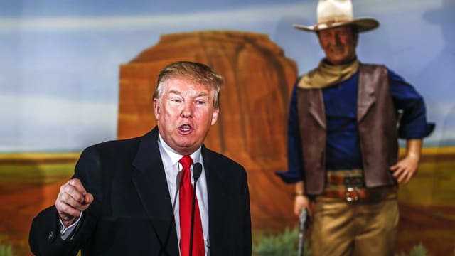 Ein Mann spricht vor einer John-Wayne-Statue. Ein Mann spricht vor einer John-Wayne-Statue.