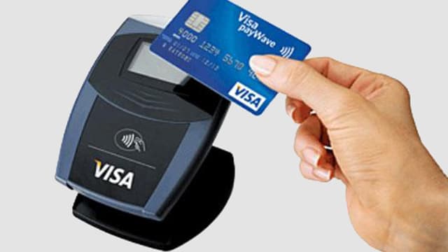 Eine Frau hält eine Visa-Karte an ein Lesegerät. Eine Frau hält eine Visa-Karte an ein Lesegerät.