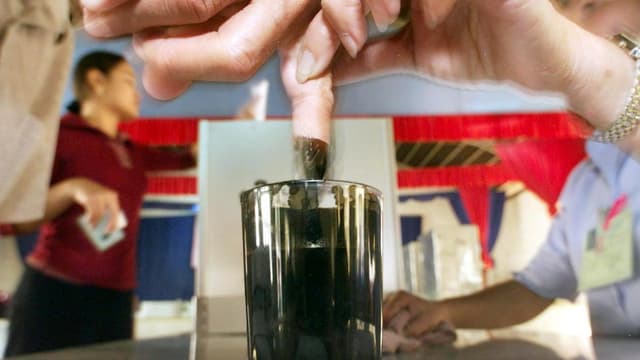 Ein Finger wird in Tinte getunkt Ein Finger wird in Tinte getunkt