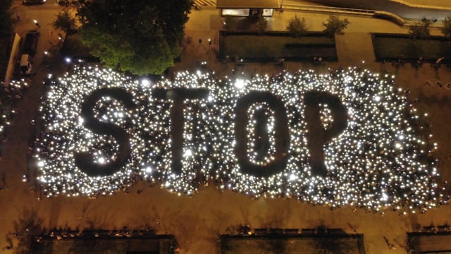 Demonstranten bilden einen Stop-Schriftzug mit Lichtern Demonstranten bilden einen Stop-Schriftzug mit Lichtern