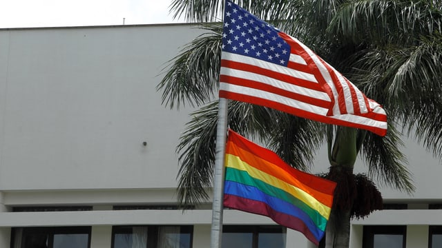 US- und Regenbogenfahne an einem Mast. US- und Regenbogenfahne an einem Mast.