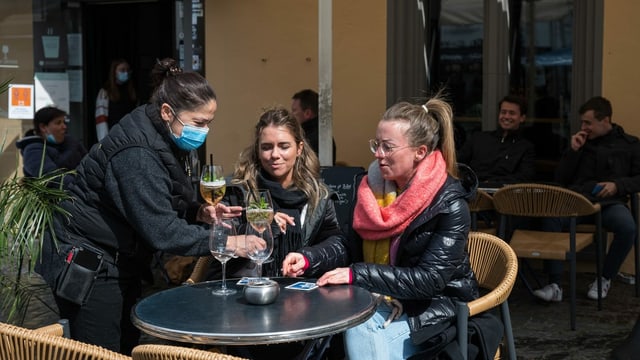 Kellnerin mit Maske serviert zwei Frauen draussen Getränke Kellnerin mit Maske serviert zwei Frauen draussen Getränke