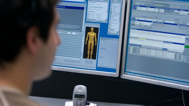 Telefonist am Computer. Auf Bildschirm ist Skizze des menschlichen Körpers zu sehen. Telefonist am Computer. Auf Bildschirm ist Skizze des menschlichen Körpers zu sehen.