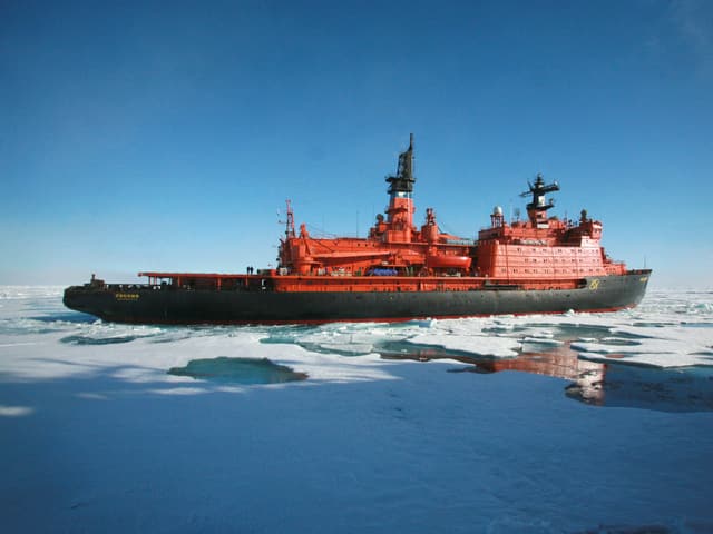 Ein roter Eisbrecher durchkreuzt das Arktische Meer.