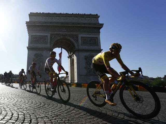 Fahrer fahren am Arc de Triomphe vorbei.