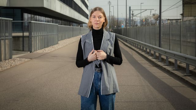 eine junge Frau steht mit einem Anzugs-Muster auf einer Strasse eine junge Frau steht mit einem Anzugs-Muster auf einer Strasse