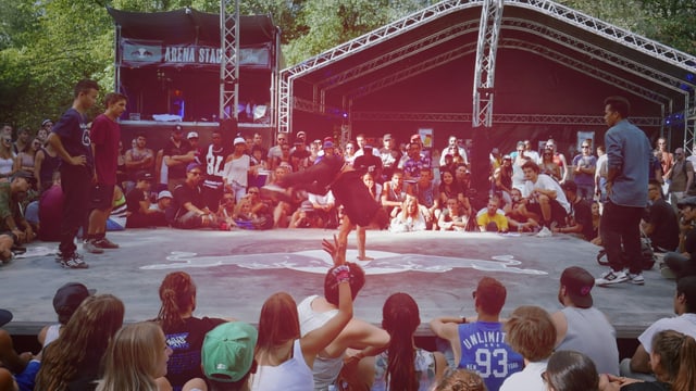 eine Arenaförmige Bühne, umringt von Menschen die ein Breakdance Battle verfolgen eine Arenaförmige Bühne, umringt von Menschen die ein Breakdance Battle verfolgen