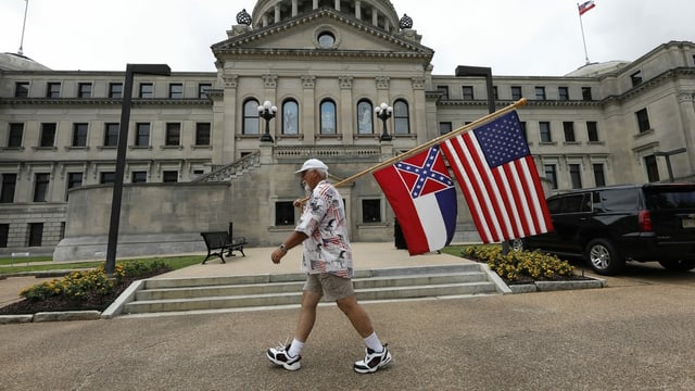 Ein Mann mit einer Flagge Mississippis und der US-Flagge Ein Mann mit einer Flagge Mississippis und der US-Flagge