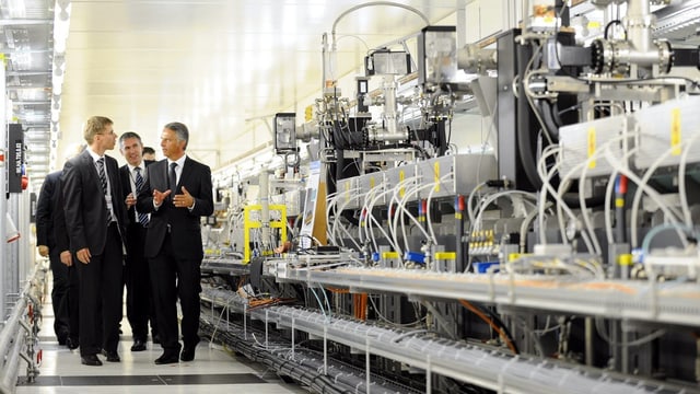 Delegation von Männern im Anzug läuft durch den mit Technik vollgestopften Gang des Swissfel Delegation von Männern im Anzug läuft durch den mit Technik vollgestopften Gang des Swissfel