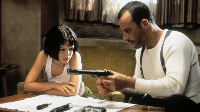 Junges Mädchen sieht einem Mann zu wie er eine Waffe lädt Junges Mädchen sieht einem Mann zu wie er eine Waffe lädt