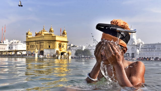 Ein Sikh nimmt ein rituelles Bad, im Hintergrund der Goldene Tempel von Amritsar. Ein Sikh nimmt ein rituelles Bad, im Hintergrund der Goldene Tempel von Amritsar.
