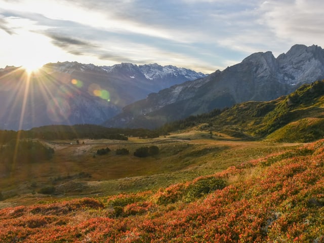 In den Bergen verfärbt sich auch vieles herbstlich. Die Sonne geht hinter dem Berg unter. In den Bergen verfärbt sich auch vieles herbstlich. Die Sonne geht hinter dem Berg unter.