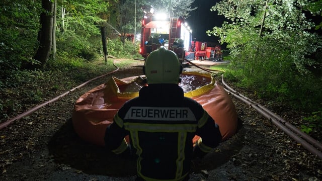 Feuerwehrmann vor Wasserbecken im Wald bei Nacht. Feuerwehrmann vor Wasserbecken im Wald bei Nacht.