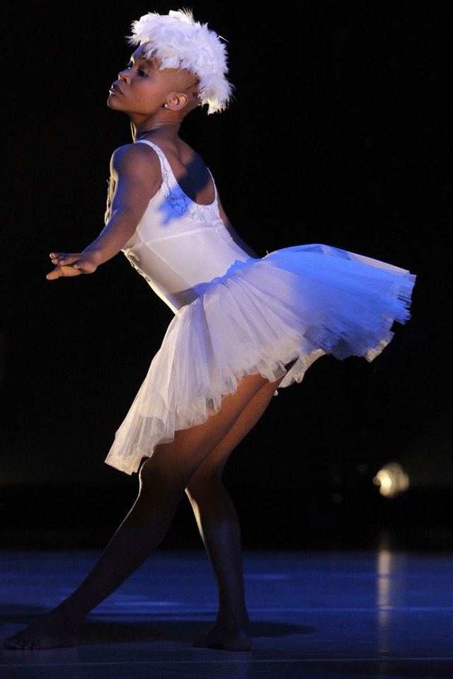 Die Tänzerin Dada Masilo, tanzend in einem weissen Tutu, mit weissen Federn auf dem Kopf. Die Tänzerin Dada Masilo, tanzend in einem weissen Tutu, mit weissen Federn auf dem Kopf.