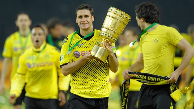 Dortmunds ehemaliger Captain Sebastian Kehl hält den DFB-Trophäe in den Händen und marschiert mit seinen Teamkollegen in die Fankurve. Dortmunds ehemaliger Captain Sebastian Kehl hält den DFB-Trophäe in den Händen und marschiert mit seinen Teamkollegen in die Fankurve.