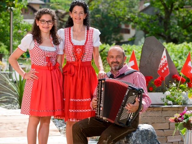 Carina und Mutter im roten Dirndl. Papa mit Akkordeon. Carina und Mutter im roten Dirndl. Papa mit Akkordeon.