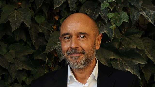 Linus Reichlin steht vor einer Hecke und lächelt in die Kamera. Linus Reichlin steht vor einer Hecke und lächelt in die Kamera.