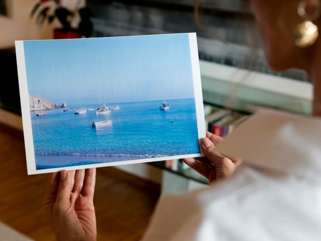 Eine Frau betrachtet ein Bild mit Meer und Schiffen. Eine Frau betrachtet ein Bild mit Meer und Schiffen.