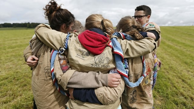 eine Gruppe junger Pfadfinderinnen und Pfadfinder umarmt sich