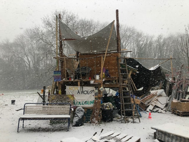 Provisorische Hütten aus Holz und Blachen im Schnee.