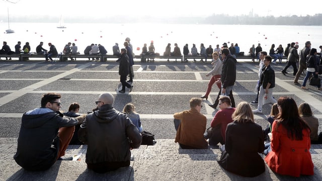 Viele Menschen sitzen auf den Steintreppen am Ufer des Zürichsees an einem sonnigen Spätwinter-Tag. Viele Menschen sitzen auf den Steintreppen am Ufer des Zürichsees an einem sonnigen Spätwinter-Tag.