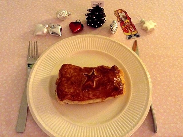 Blätzli im Butter-Blätterteig auf einem Papteller, Besteck und Weihnachtsdekoration. Blätzli im Butter-Blätterteig auf einem Papteller, Besteck und Weihnachtsdekoration.