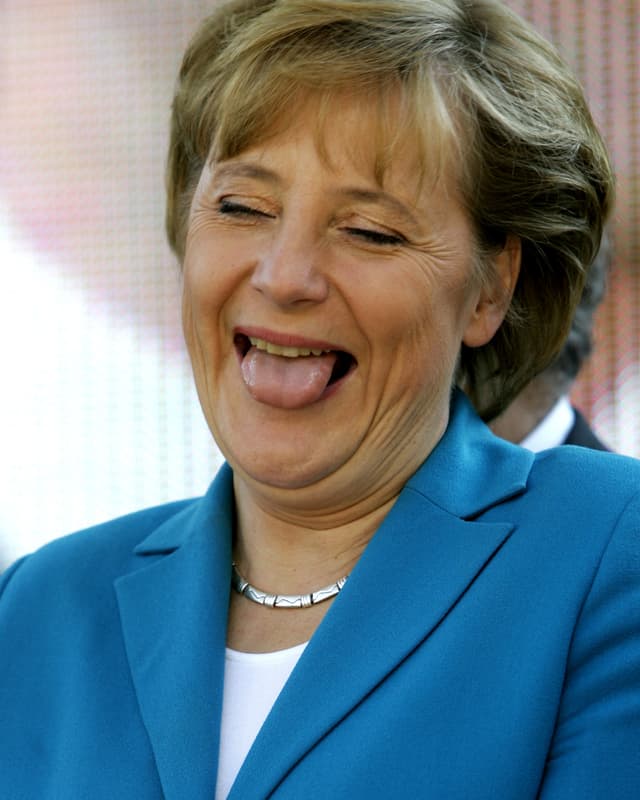 Angela Merkel lacht und streckt die Zunge dabei raus.