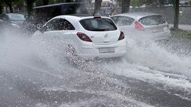 Autos fahren auf einer überfluteten Strasse im Tessin. Autos fahren auf einer überfluteten Strasse im Tessin.
