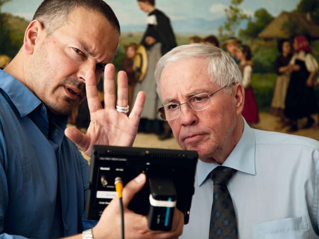 Bron und Blocher schauen auf einen Bildschirm. Im Hintergrund ein Anker-Gemälde. Bron und Blocher schauen auf einen Bildschirm. Im Hintergrund ein Anker-Gemälde.