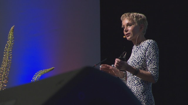 Purtret da Margrit Stamm, la professura emeritada da pedagogia a l'universitad da Friburg, che discurra al podi. Purtret da Margrit Stamm, la professura emeritada da pedagogia a l'universitad da Friburg, che discurra al podi.