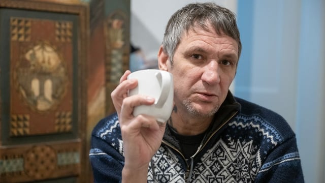 Ein Mann im Norweger-Pullover hält eine Kaffeetasse in der Hand und blick tin die Kamera. Ein Mann im Norweger-Pullover hält eine Kaffeetasse in der Hand und blick tin die Kamera.