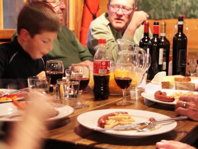 Leute sitzen an einem Tisch und Essen.