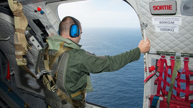 Ein Soldat blickt aus einer geöffneten Flugzeugtüre auf das Meer. Ein Soldat blickt aus einer geöffneten Flugzeugtüre auf das Meer.