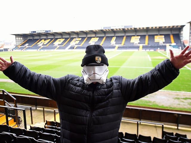 Fan mit Stormtroopers-Helm in leerem Fussballstadion.