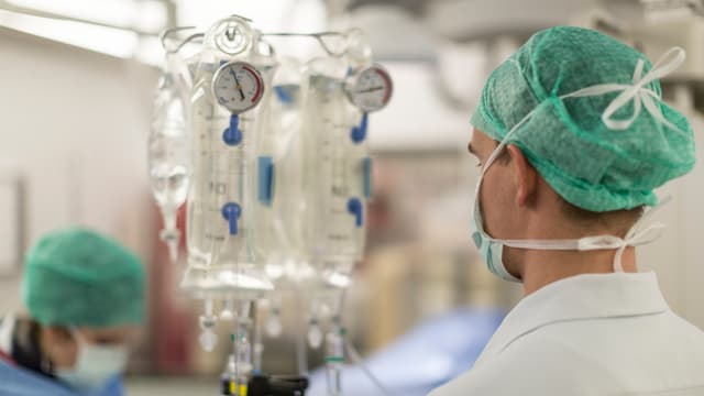 Mediziner beobachtet Anzeigen an Infusionsständer. Mediziner beobachtet Anzeigen an Infusionsständer.