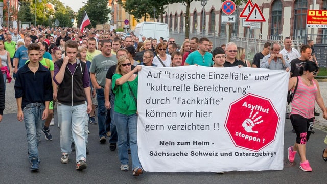Demonstranten in Heidenau tragen ein asylkritisches Transparent vor sich her. Demonstranten in Heidenau tragen ein asylkritisches Transparent vor sich her.