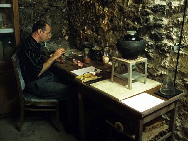 Armen Sahakijan in einem Raum mit steinigen Wänden. Er arbeitet an einem Tisch. Armen Sahakijan in einem Raum mit steinigen Wänden. Er arbeitet an einem Tisch.