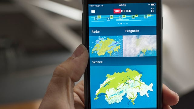 Ein Hand hält ein Handy, auf dem eine Wetter-App angezeigt wird. Ein Hand hält ein Handy, auf dem eine Wetter-App angezeigt wird.